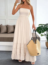 Woman wearing a sleeveless halter neck tiered maxi dress with frill and smocked details